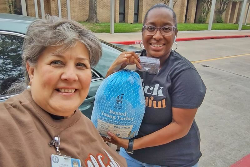 Alice Wimberly, a student services volunteer, delivers a turkey donated by Sylvan Learning Center and a gift card.
